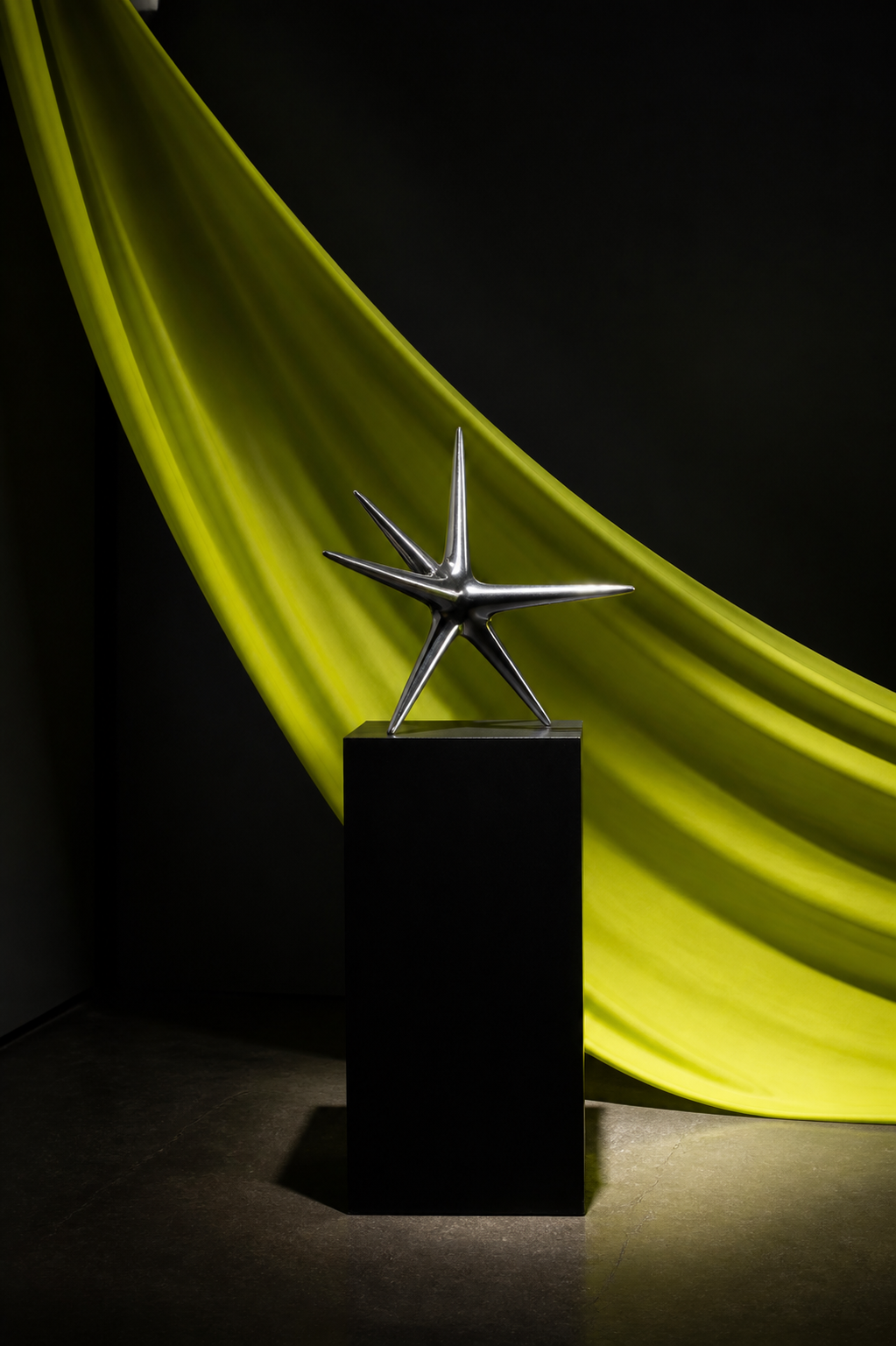 An abstract silver object displayed in a dramatic gallery setting